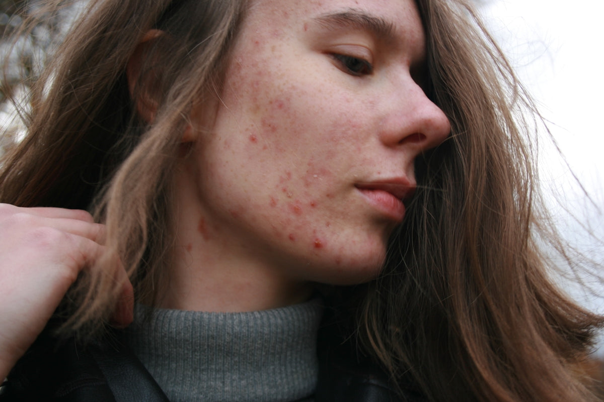 A woman with long brown hair wearing a grey turtleneck sweater